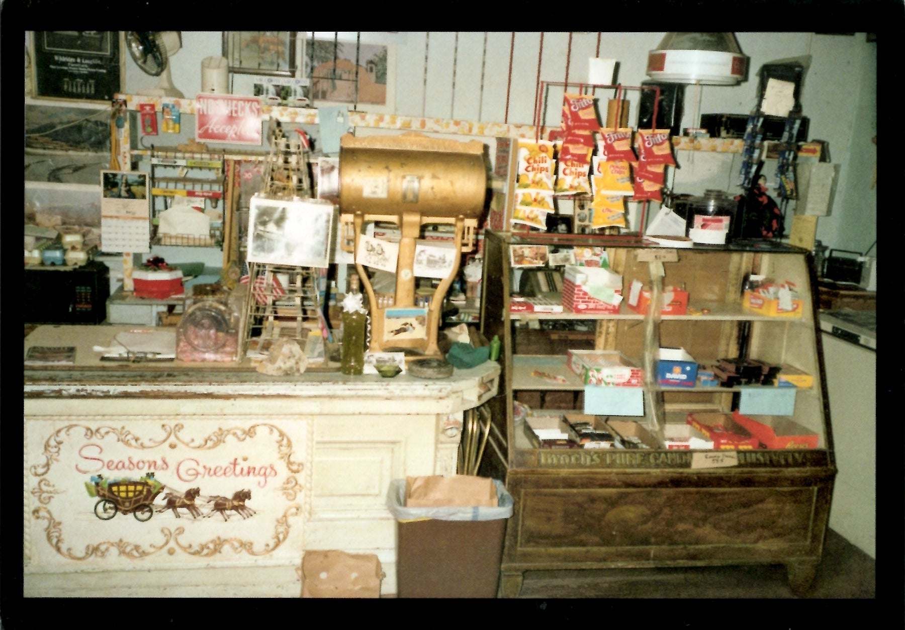 Vintage store interior with a Seasons Greetings on counter side, and shelves stocked with old timey products.